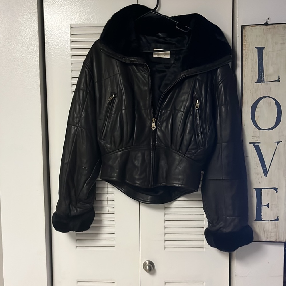 Thick and cozy black leather jacket with fur around the color and wrists.
